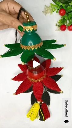 a person holding a green bell with red and yellow decorations on it's side