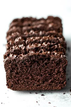 a close up of a chocolate cake on a white surface with one slice cut off