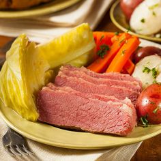 corned beef, potatoes and carrots on a yellow plate with bread in the background