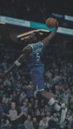 a basketball player jumping up to dunk the ball in front of an arena full of people