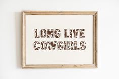 a wooden frame hanging on the wall that says long live cowgirls in brown and white