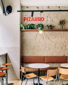 the interior of a restaurant with tables and chairs, plants on the wall above them