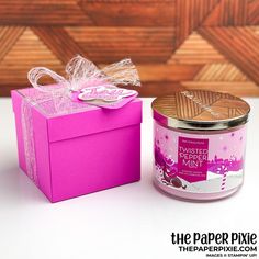 a pink gift box next to a purple candle