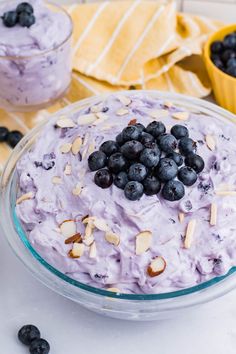 a bowl filled with blueberries and almonds on top of a table next to two bowls