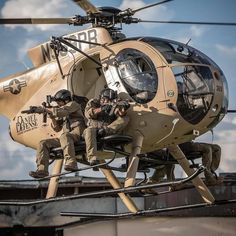 three men in uniform are sitting on the back of a helicopter