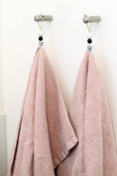 two pink towels hanging on the wall next to each other