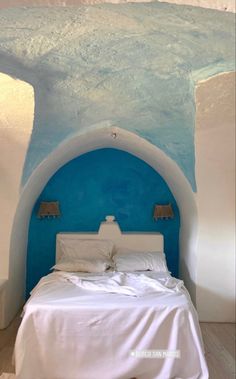 a bed with white sheets and pillows in a room that looks like an ice cave