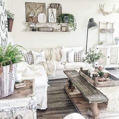 a living room filled with lots of furniture and plants on top of wooden tables in front of a white couch