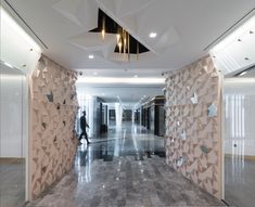 a person walking down a long hallway between two walls that have geometric designs on them