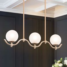 a chandelier with three white glass balls hanging from it's arms in a dining room