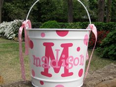 a white bucket with pink polka dots and the word madison painted on it is sitting in front of some bushes