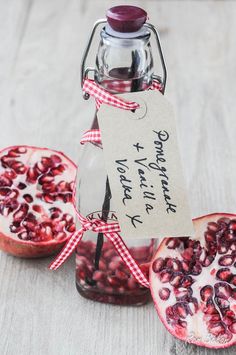 pomegranate in a glass jar with a tag attached to the bottle and two pieces of fruit around it