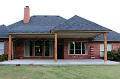 a red brick house with a covered porch and large grass area next to the front door