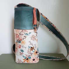 a flowered bag sitting on top of a green table next to a white wall