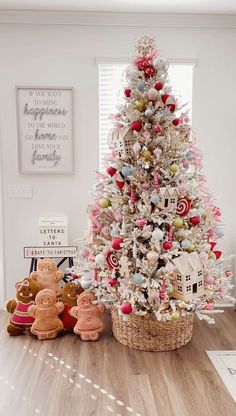 a white christmas tree with pink and red ornaments in a basket next to stuffed animals