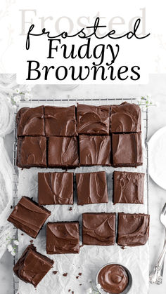 chocolate frosted fudge brownies on a cooling rack with spoons next to it