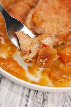 a close up of food on a spoon in a bowl with meat and sauces