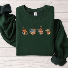 Fall Embroidered Sweatshirt Mushroom with Autumn Leaves Crewneck Embroidered Fall TShirt, Fall Top for Her, MADE IN USA There are two brands we use: Gildan and our own brand BeePro Handmade. Comfort Colors, Bella Canvas, and other brands are available upon request at a different price. If interested in adding embroidery to the sleeve please go to this listing: https://www.etsy.com/listing/1674502020 Because it is made to order, we don't accept the return or exchange unless we make a mistake We a Green Long Sleeve T-shirt With Custom Embroidery, Long Sleeve T-shirt With Multicolor Embroidery, Green Embroidered Long Sleeve T-shirt, Green Floral Embroidery Tops For Fall, Green Floral Embroidered Tops For Fall, Fall Cotton T-shirt With Floral Embroidery, Cotton Fall Sweatshirt With Mushroom Print, Green Cotton Sweater With Embroidered Graphics, Cotton Sweatshirt With Mushroom Print For Fall