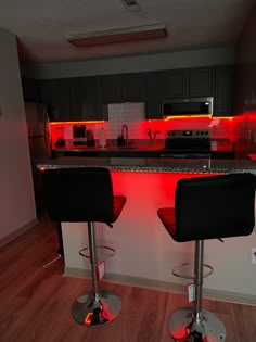 two bar stools sit in front of a kitchen counter with red lights on it