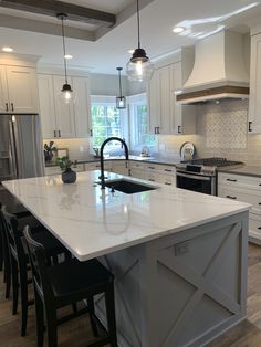 a large kitchen with an island in the middle and white cabinets on both sides, surrounded by black chairs