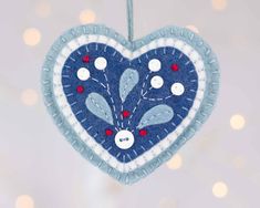 a blue and white heart ornament hanging from a string with lights in the background