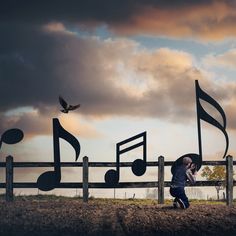 a person walking past musical notes on a fence with a bird flying in the background