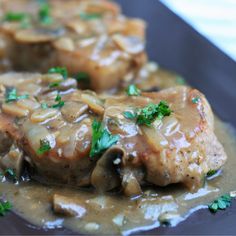 some meat and gravy on a black plate