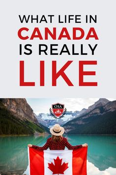 the canadian flag is being held up in front of a lake with mountains and trees