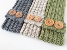 four different colors of knitted scarves with wooden buttons on the sides and one has a button in the middle