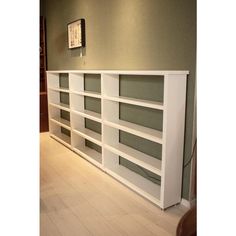 a white bookcase sitting on top of a hard wood floor next to a wall