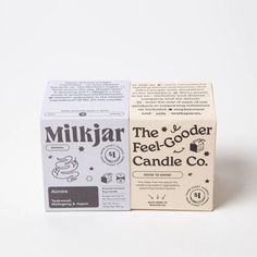 two boxes of milk sitting next to each other on a white surface, one with the word'the gooder candle co'printed on it