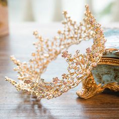 a gold tiara sitting on top of a wooden table next to a book and vase