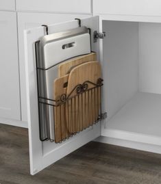 a kitchen cabinet with cutting boards and knives in the bottom drawer, which is open