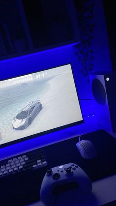 a computer screen with a car on it next to a game controller and keyboard in front of the monitor