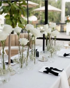 there are many vases with flowers in them on the long table at this wedding reception