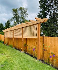 a wooden fence is lined with plants and flowers