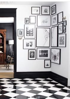 a room with black and white checkered flooring, framed pictures on the wall