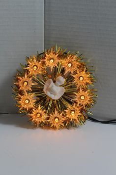 a christmas wreath with lights on it and a bow hanging from the center, in front of a wall