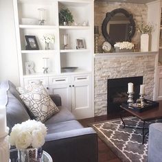 a living room filled with furniture and a fire place under a mirror on the wall