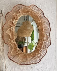 a mirror hanging on the wall next to a potted plant and wicker basket