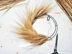 a pair of scissors sitting on top of a table next to some stalks of wheat