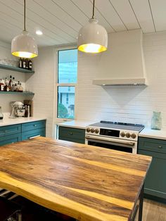 a large wooden table sitting in the middle of a kitchen next to a stove top oven