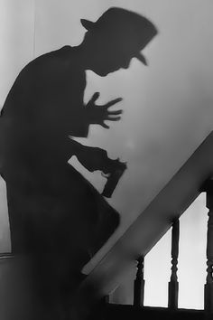 the shadow of a man standing on top of a stair case next to a hand rail