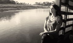 a woman sitting on a bench next to a body of water