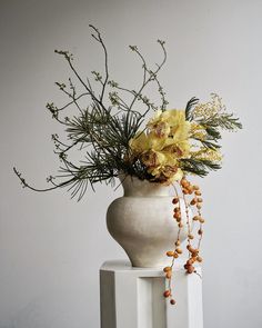 a white vase with yellow flowers in it