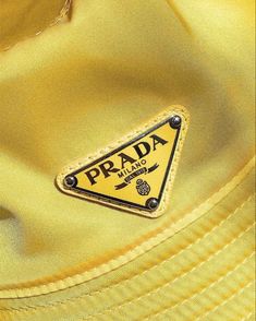 a yellow prada shirt with a triangle patch on it