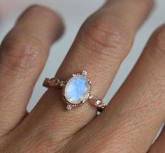 a woman's hand wearing a ring with an oval shaped blue and white stone