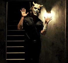 a man in a creepy mask is holding his hands up to the light that is on