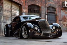 a black car parked in front of a brick building