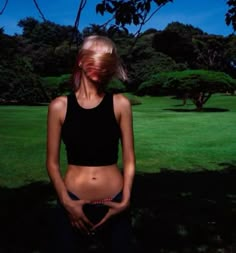 a woman standing in the grass with her belly exposed